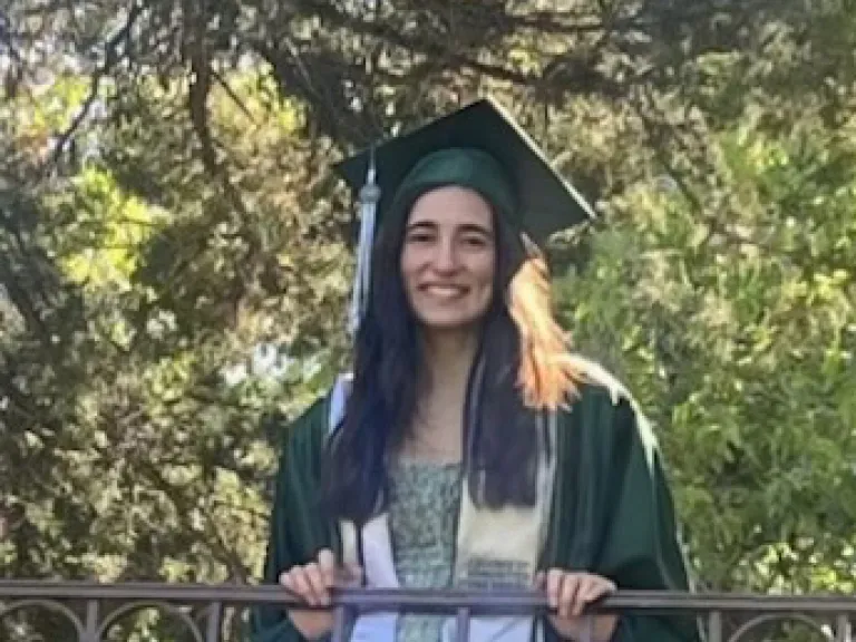 a woman wearing a graduation cap and robe standing outdoors