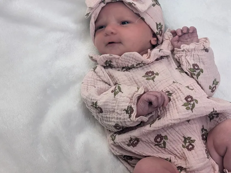 Baby girl wearing a pink outfit and a pink bow headband