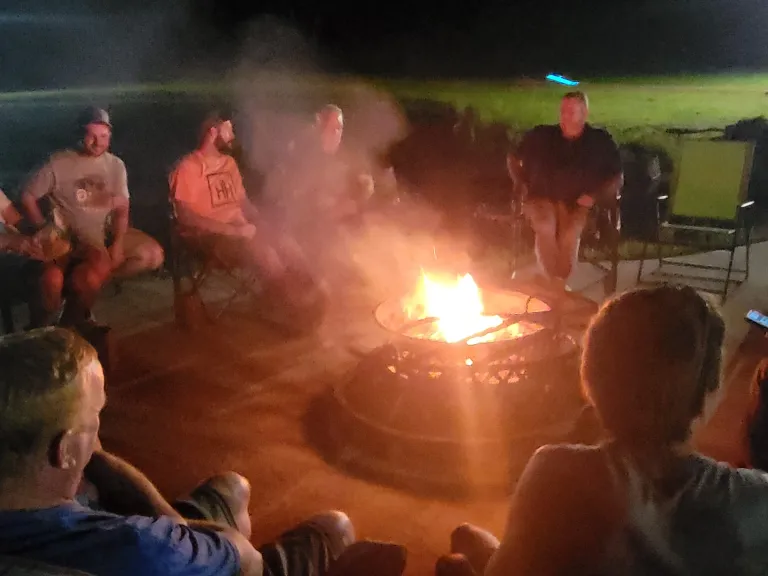 men gathered around a glowing campfire