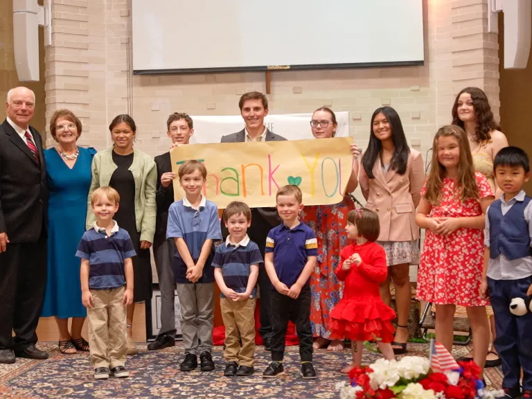 a group of children and teenagers with a pastor and his wife standing to the side