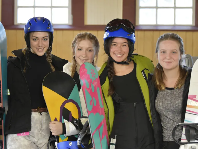 Join us this winter break for an exciting and spiritually-uplifting time at camp! four girls with snowboarding equipment