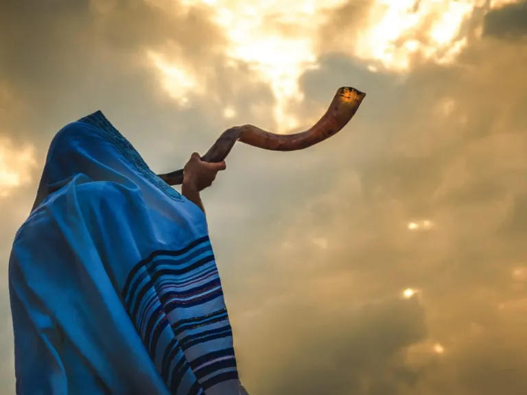 a man in biblical robes blowing a shofar