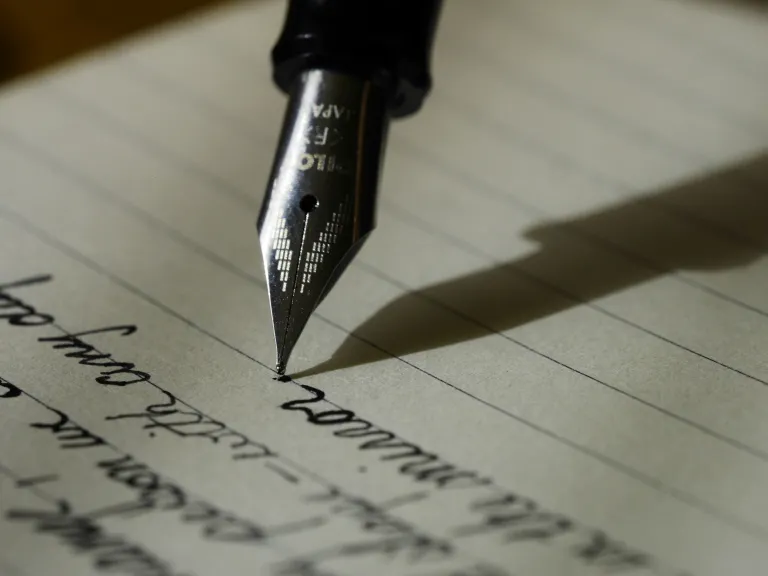 a fountain pen writing in black ink on lined paper