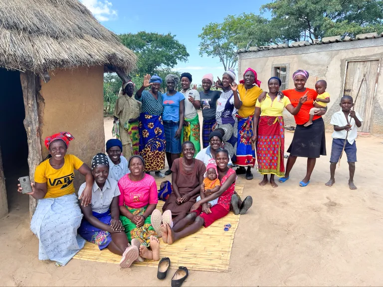 Church family in Zimbabwe a group of people standing and sitting outdoors beside a small hut