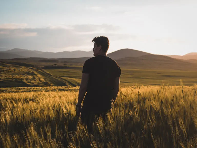 A young man standing in a wheat field.