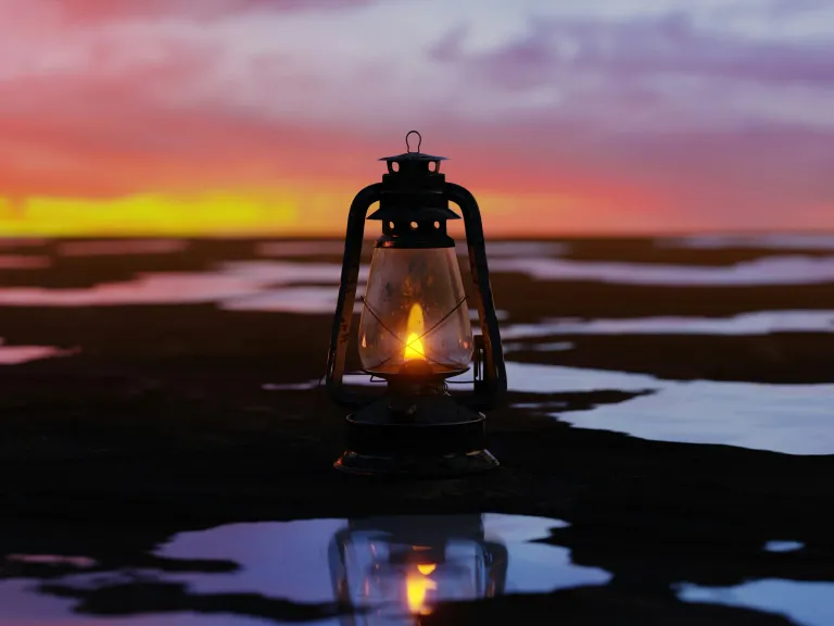a lantern sitting surrounded by puddles that reflect the sunset colors of the sky