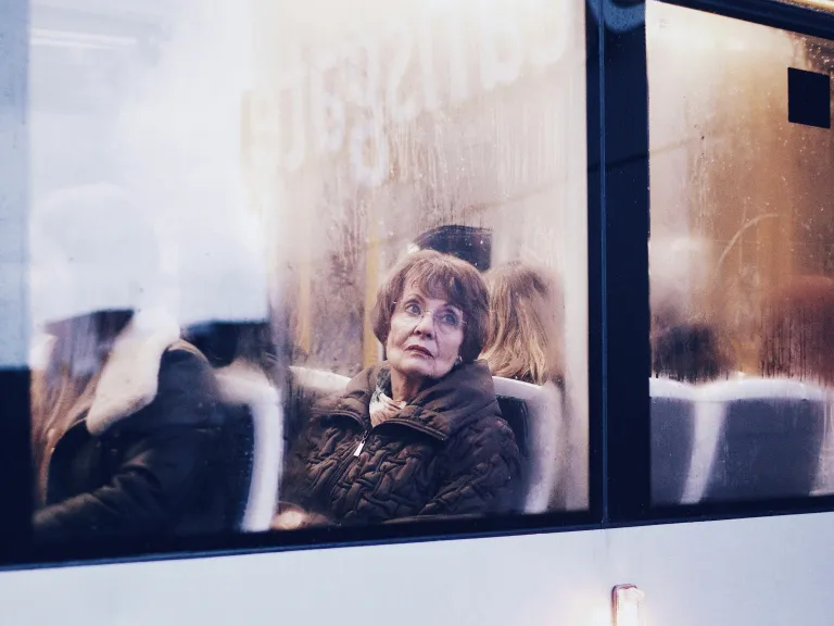 A woman sitting in a bus looking out the window.