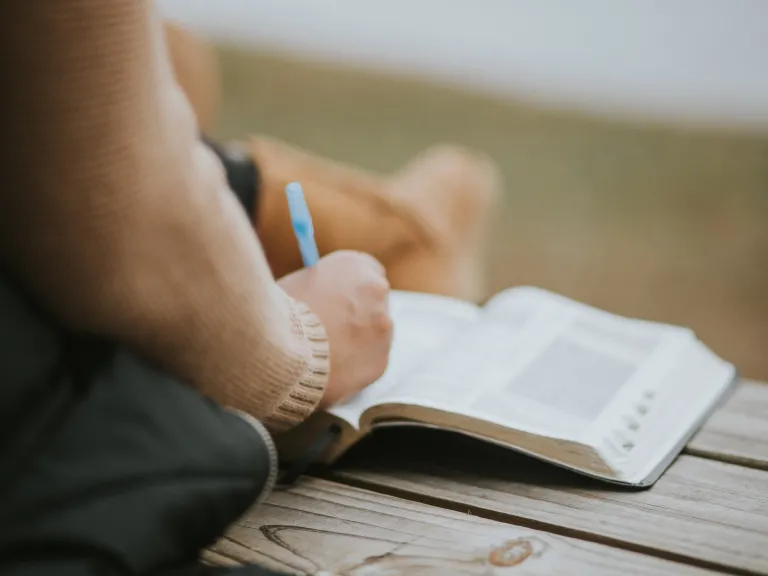 A person writing notes in a Bible.