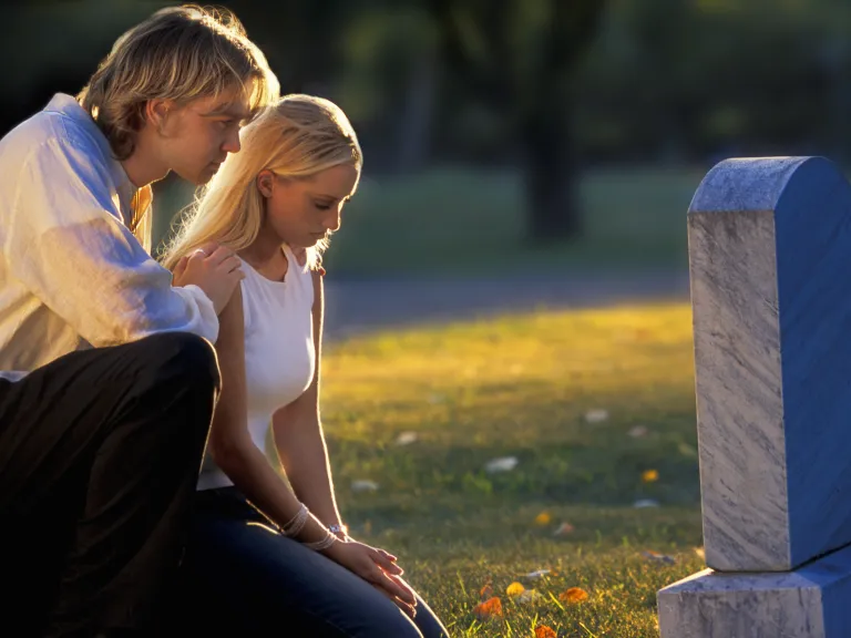 A young couple by a grave stone.