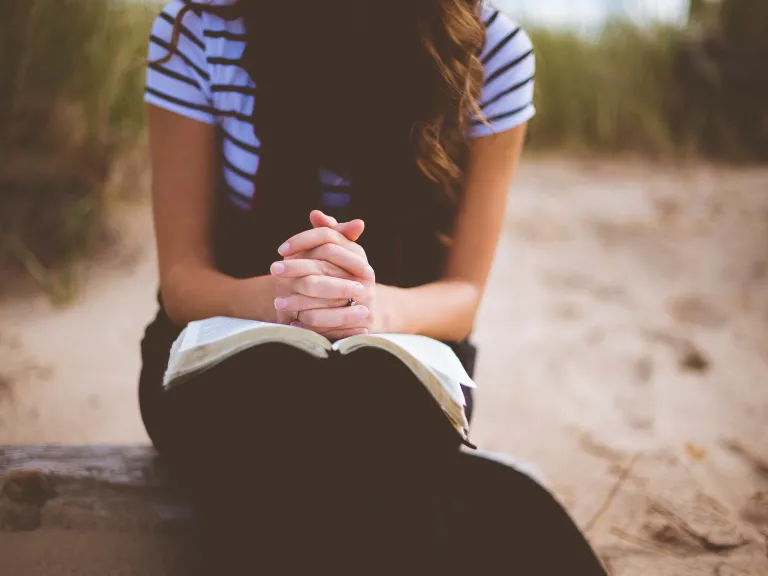 Our love for and commitment to Jesus Christ and God the Father must be more important to us than any other relationship. A woman with a Bible on her lap.
