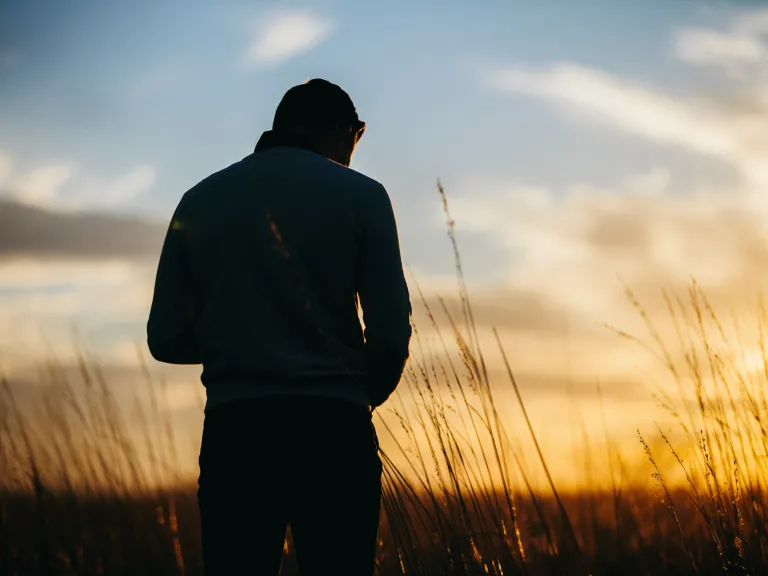 A person in a field at sundown.