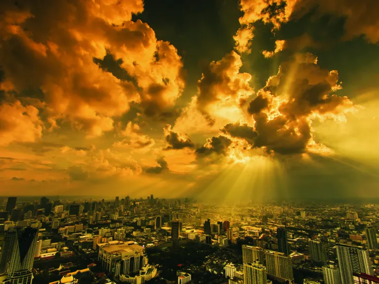 Sun rays shining through clouds on a city.