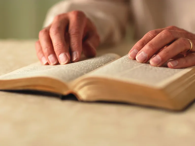A woman turning the pages of a Bible.