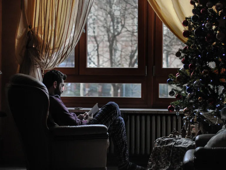 What do the major symbols of Christmas— Santa Claus, decorated trees, mistletoe—have to do with the birth of the Savior of mankind? A man sitting in a chair across from a Christmas tree.
