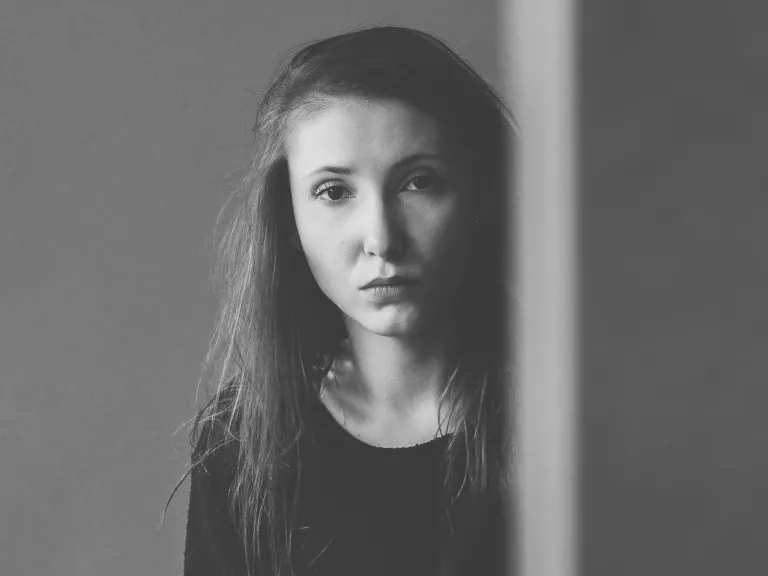 I thought I could fix him with my advice and suggestions. I was in denial and trying to control what was not mine to control; I was in God’s way, and I had a lot to learn myself. A young woman looking from behind an edge of a wall.