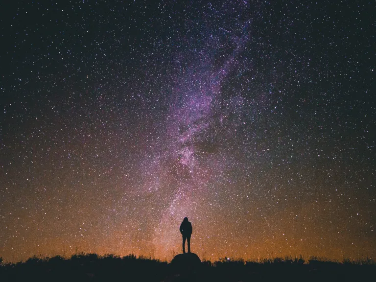 A person standing at night with stars in the background.