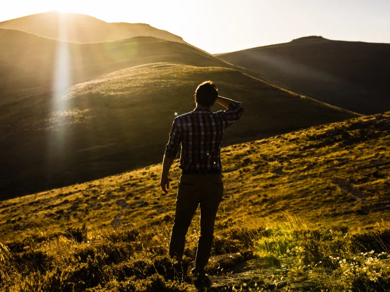 This new life we live in the grace of God is shown by the fruits of righteous works. So then grace, God’s kindness and goodness toward us, motivates us to change and helps create the desire to receive the divine nature, the mind of God. A man looking out over a vista of hills with the sun in his eyes.