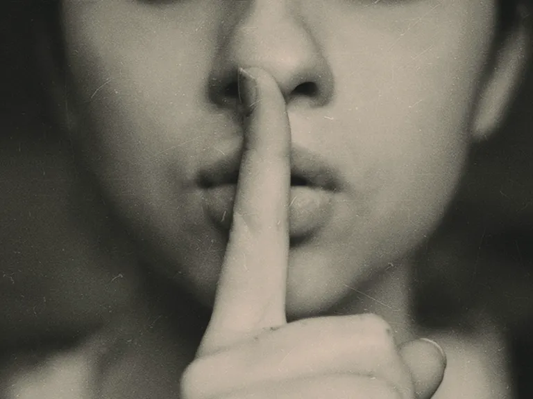 Picture of a person with finger over their lips.