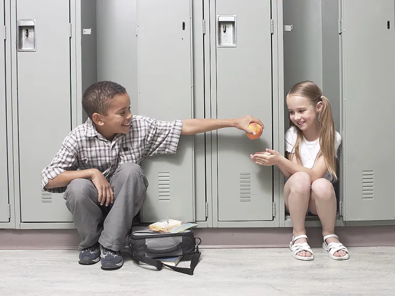When children are taught proper moral values at an early age, they are likely to maintain those character traits for the remainder of their lives. A young boy giving an apple to girl a school.