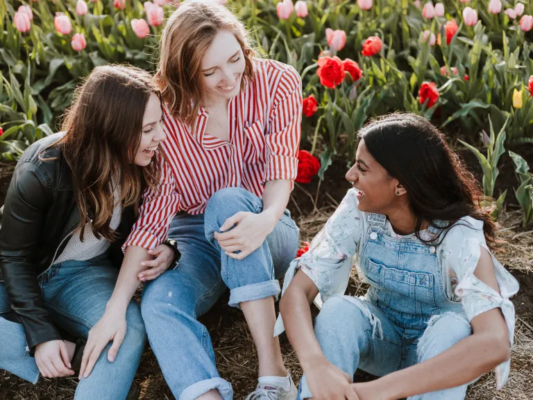Group of three girl friends sitting together, smiling and enjoying each other's company.