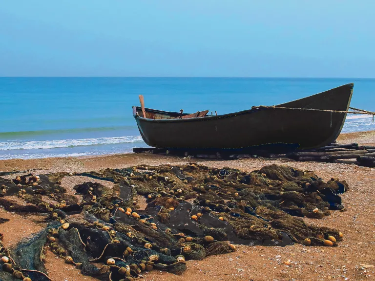 What He wants is that you heed His words, leave your nets and obey His directive of “Follow Me.” A boat on a sandy shore with nets.
