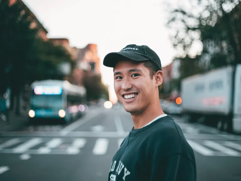 We must nurture peace and make it a part of our lives and character. a smiling man with a city street background