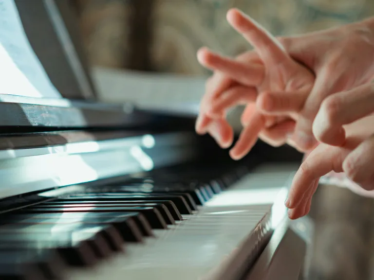 However rudimentary we may feel, our Great Master is augmenting and supplementing to create a masterpiece within those He calls His own. A piano instructor guiding the fingers of child on the piano.