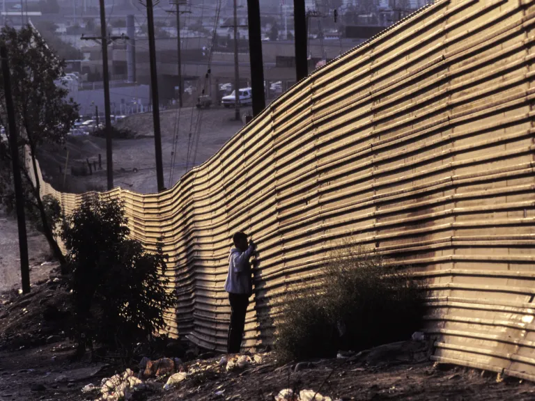 People standing by a border wall.