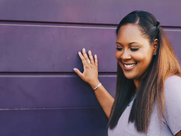 Many feminists reject Christianity as anti-woman, but the Bible reveals that women's role is an honorable one. woman touching a purple wall
