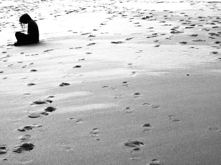 A woman sitting on deserted beach.
