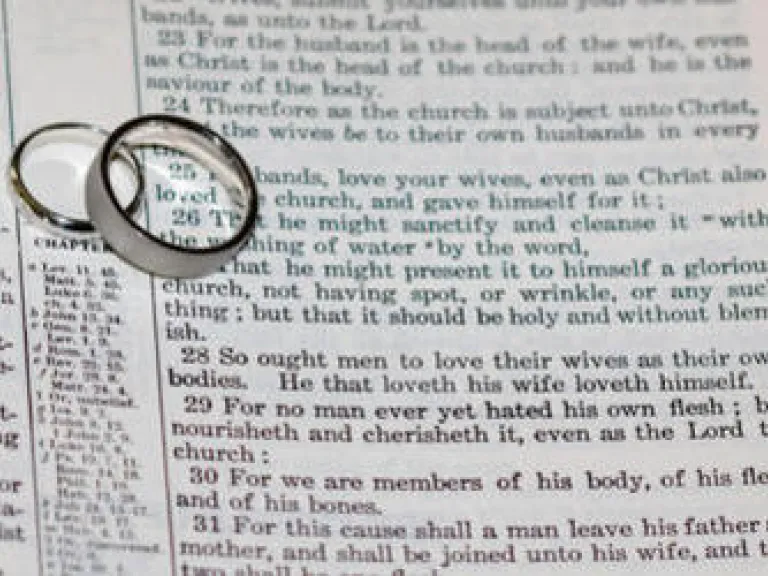 The Ultimate Purpose of Marriage Wedding rings on top of Bible scripture - Ephesians 5:22-21