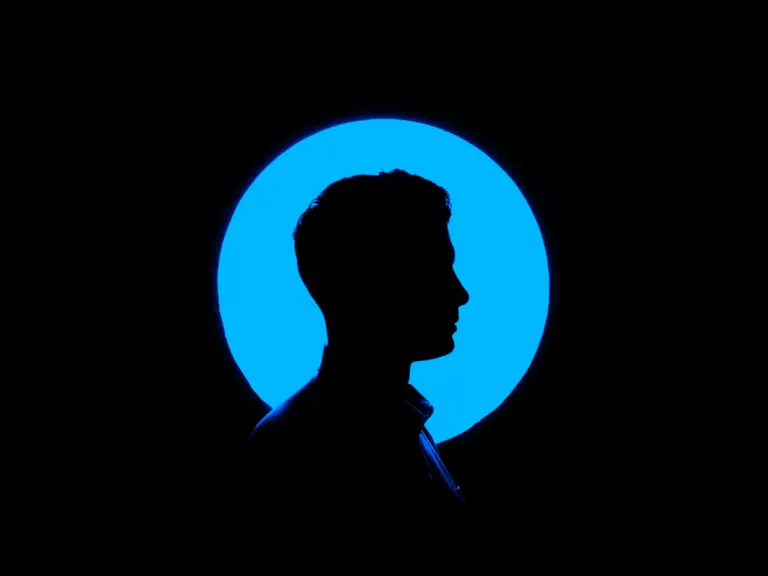 a man's head silhouetted against a blue circle on a black background