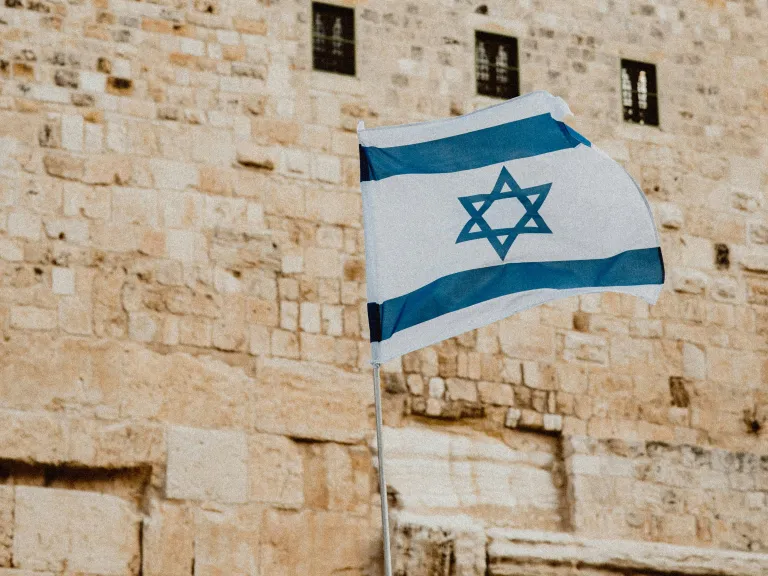 With God all things are possible. Jerusalem, Israel and the whole world will finally have peace, a peace wisely orchestrated by the Prince of Peace, Jesus Christ. Photo of israeli flag in front of stone wall.