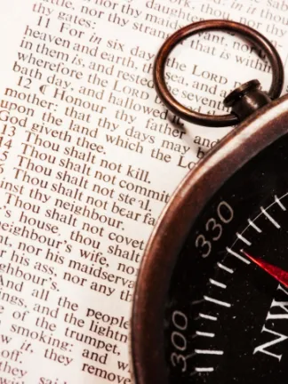 Compass laying on top of a Bible opened to Exodus 20 - where the 10 Commandments are listed.
