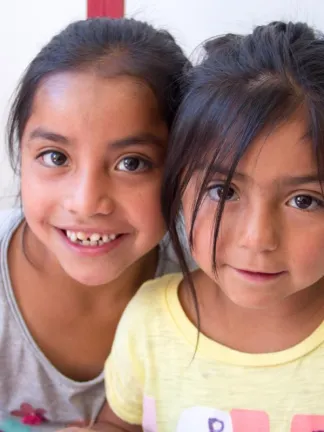 Two girls in school chairs at Eagle's Nest Orphanage