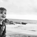 a little boy walking along the beach