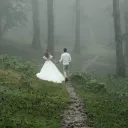a bride and a groom walking outdoors into the mist