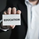 a man holding a business card that says "education"