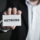 a man holding a business card that says "network"