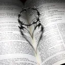 a crown of thorns casting a heart-shaped shadow on a Bible opened to a passage about Christ