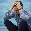 a man sitting and holding his head in his hands