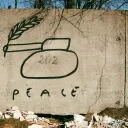 Hand-drawn tank on cement wall with peace written underneath.