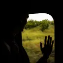 Silhouette of a man looking out train window with hand on the window