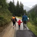 A family of three walking on a road in the mountains