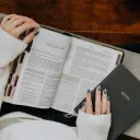 A woman reading a Bible with a notebook.