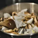 Vegetable and mushrooms being sauted in a pan.