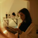 a woman holding a book, reflected in a mirror