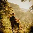 a woman leaning on a railing and looking out over a hillside drenched in golden sunlight