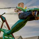 A little boy swinging on a swingset.