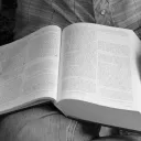 A person holding a Bible on their lap.